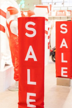 Giyim mağazasının girişinde indirimli tabela, beyaz kelimelerle dolu büyük kırmızı paneller. Mevsimlik indirim teklifi geldi. İndirim ve Kara Cuma konsepti. Moda konsepti, çevrimdışı alışveriş, tatil satışları..