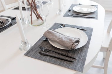 Modern evdeki beyaz tabaklı yemek masası. Pamuk dalları vazoda. Sıcak mutfak. Narsis çiçekleriyle dolu güzel bir masa.