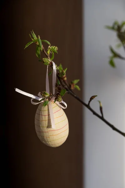 Composizione pasquale. rami di albero con piccole foglie verdi e uova di Pasqua colorate su sfondo sfocato.Concetto interior design per le vacanze di primavera — Foto Stock