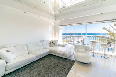 Kosta del Sol 'daki Porto Banus limanına bakan büyük beyaz kanepeli lüks bir oturma odası. 