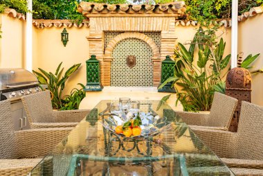 Arka planda çeşme özelliği olan bir açık hava yemek masası resmi. 