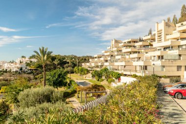 a landscape image of a block of apartments along side the gardens alongside them along the coastline of the Costa Del Sol 