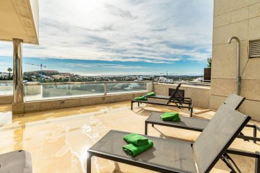 Costa Del Sol 'un Akdeniz kıyı şeridine bakan lüks bir apartmanın terasından, dinlenme odalarıyla dolu bir manzara. 