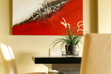 Lüks bir dairede sandalyeleri olan yemek masasındaki bir bitkinin izole edilmiş yakın çekimi.