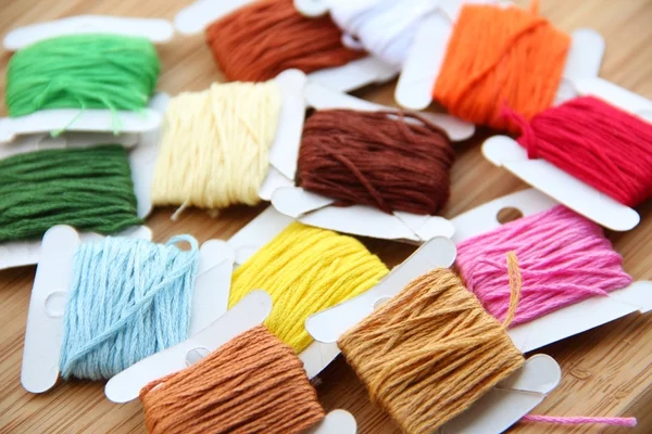 Cross-stitch set: colour palette, threads, canvas against a wooden background — Stock Photo, Image