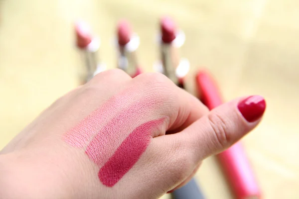 Μια γυναίκα προσπαθεί τρεις διαφορετικές αποχρώσεις κραγιόν για το χέρι της να δούμε που ταιριάζει με το χρώμα του δέρματος κατά την αγορά για μακιγιάζ — Φωτογραφία Αρχείου