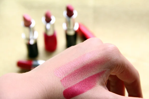 Eine Frau probiert drei verschiedene Schattierungen von Lippenstift an ihrer Hand aus, um zu sehen, welche zur Hautfarbe passt, wenn sie Make-up kauft — Stockfoto