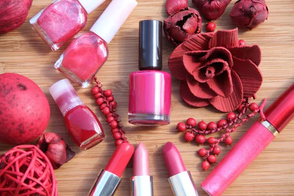 Una colección de maquillaje: lápices de labios, brillo de labios y esmaltes de uñas decorados con popurrí rojo, todo en tonos rojos y rosados aislados en blanco — Foto de Stock