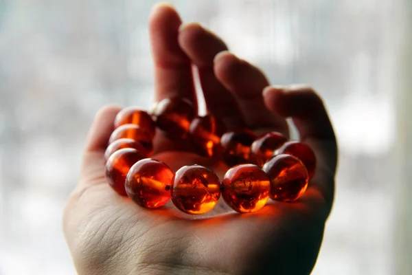 A close-up shot of a fluorescent amber bracelet shining in the sunlight — Stock Photo, Image