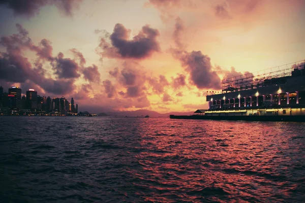 Puesta de sol en Hong Kong: vista del puerto de Victoria desde la isla de Kowloon. Algunos vintage, tonificación retro añadido — Foto de Stock