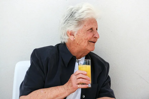 Velha senhora inteligente com suco de laranja — Fotografia de Stock