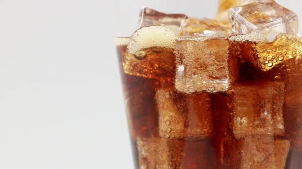 アイスキューブのクローズアップでコーラを入れてください 氷をグラスに入れてコーラ コーラソーダを閉めろ 白い背景にコーラを飲むの回転ガラス — ストック動画