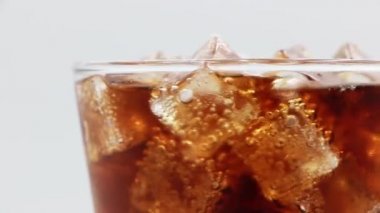 Bardakta buzlu kola. Kola Gazozu yakın plan. Beyaz arkaplanda dönen kola bardağı.