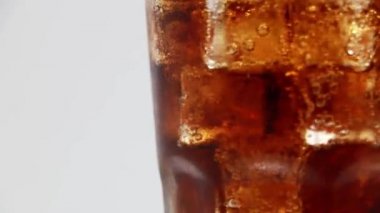 Bardakta buzlu kola. Kola Gazozu yakın plan. Beyaz arkaplanda dönen kola bardağı.