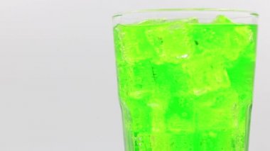 Bardakta buzlu, yeşil köpüklü su. Beyaz zemin üzerinde yeşil köpüklü su içeceği.