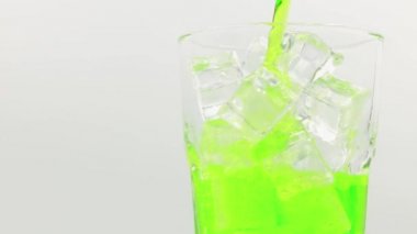 Yakından buzlu yeşil köpüklü su dökülüyor. Bardakta buzlu, yeşil köpüklü su. Beyaz zemin üzerinde yeşil köpüklü su bardağı dönüşümlü.