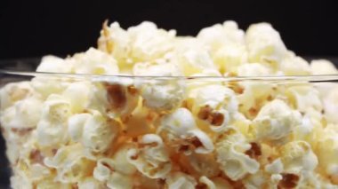 Patlamış mısırı siyah arka planda dönen bir bardağa boşalt.