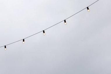 Ampul çelenkleri gri gökyüzüne karşı