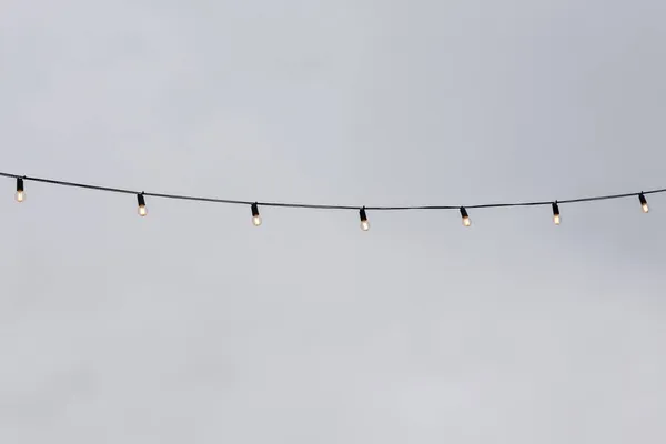 Light bulb garlands against the grey sky — Stock Photo, Image