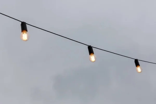 Guirnaldas bombilla contra el cielo gris —  Fotos de Stock