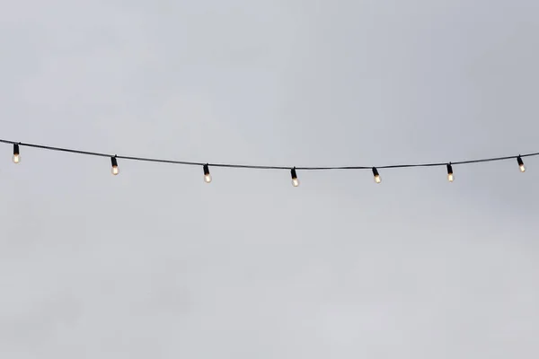 Žárovkové věnce proti šedé obloze Stock Fotografie