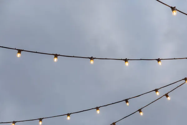 Гірлянди з лампочками на тлі сірого неба Стокова Картинка
