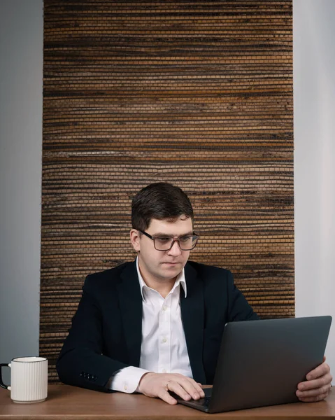 Laptop ekranına bakan bir adamın portresi. Gözlüklü iş adamı internette çalışıyor.