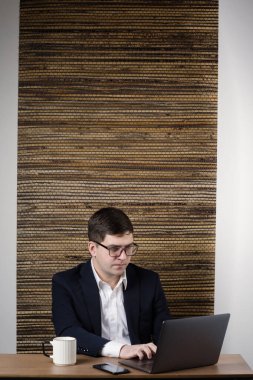 Laptop ekranına bakan bir adamın portresi. Gözlüklü iş adamı internette çalışıyor.