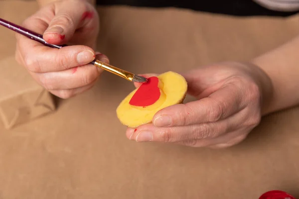 Sello de patata en forma de corazón en papel artesanal. El proceso de decorar un regalo para el Día de San Valentín. Preparándose para la celebración del 14 de febrero. — Foto de Stock