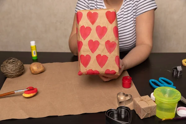 Sello de patata en forma de corazón en papel artesanal. El proceso de decorar un regalo para el Día de San Valentín. Preparándose para la celebración del 14 de febrero. — Foto de Stock