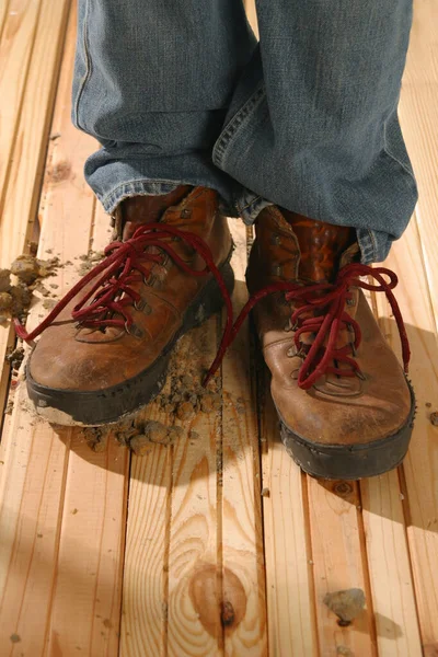 一幅工人的鞋子的照片 背景是木制的 周围有几块潮湿的水泥 图库照片