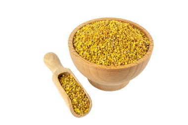 Tahta kasede arı poleni ve beyaz arka planda izole edilmiş kepçeler. İltihabı azaltmak için doğal bitkisel ilaçlar, grip, karaciğer sağlığını arttırır, bağışıklık sistemini güçlendirir, stresi azaltır ve beslenme desteği olarak kullanılır..