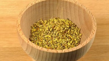 Arı poleni ağır çekimde ahşap kaseye düşüyor. İltihabı, gribi, karaciğer sağlığını iyileştiren, bağışıklık sistemini güçlendiren doğal bitkisel ilaçlar..