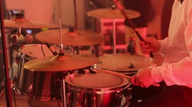 Davulcu ıslak davula vurdu. Genç adam sahnede davul çalıyor. Çalarken davullar ve ziller. Bateri seti, davul seti karanlıkta, davulcu bir konser veriyor. Konser. Neon ışığı