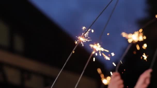 Feche as mãos segurando grupo sparklers de amigos comemorando acenando fogos de artifício sparkler dançando desfrutando de festa de véspera de novos anos se divertindo celebração de férias à noite. Bengala Flicker desfocado Bokeh. — Vídeo de Stock