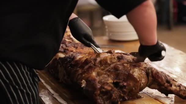 Male chef prepares meat with crispy crust and spices baked on grill in kitchen. Cook in apron puts large fried piece of meat on cutting Board. Cooking delicious and delicious meat — Stock Video