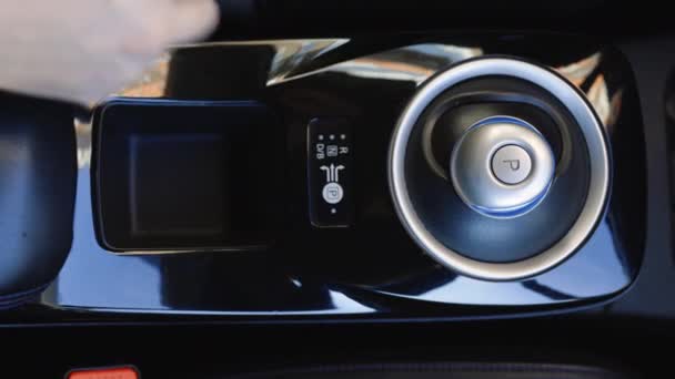 ドライバーアダムは、モードが含まれています高級電気自動車のギアレバー自動変速機上のドライブ。人間の手はスティックシフトトランスミッションエコカーを制御します。車を起動するためのドライブボタン. — ストック動画