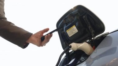 Erkek el, EV vagonuna güç bağlantısını kesiyor. Adam kablolu elektrikli aracın fişini çekti. Sürücü, elektrikli aracının şarjını çıkarıyor. Ekoloji alternatif enerjisini gelecek sürdürülebilir olarak kaydet