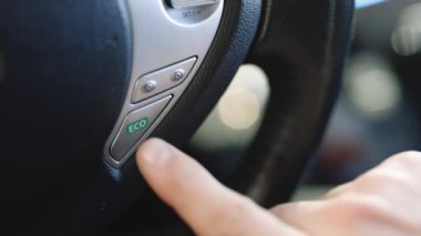 Elektrikli araba sürücüsü, eko düğmeye basıyor, direksiyon simidi, çevre koruması. Elektrikli arabadaki eko tuşuna bas.