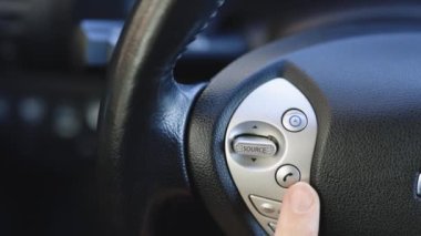 Bir arabanın direksiyonundaki Bluetooth tuşlarını kullanarak telefondan ücretsiz konuşmak. Düğmeli araba cep telefonu.