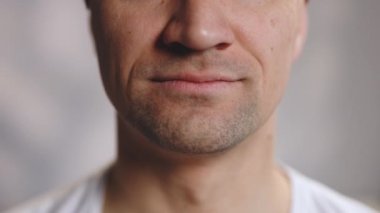 Yüze yakın gülen dişler izole edilmiş. Gülümseyen sakallı bir adamın ayrıntıları. Başarılı adam arka planda gülümsüyor. Oturma odasında gülümseyen yakışıklı adamın portresi.