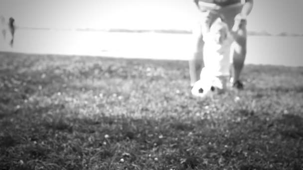 Bebê com pai brincando com bola de futebol na grama — Vídeo de Stock