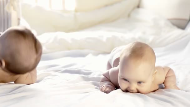 Два счастливых младенца смеются на кровати — стоковое видео