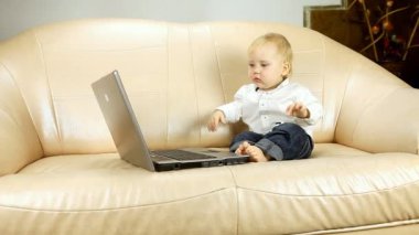 koltukta oturan çocuk ve laptop içinde görünüyor