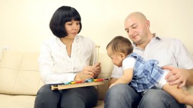 bebeğin anne ve babayla kanepede oturan gülümsüyor.