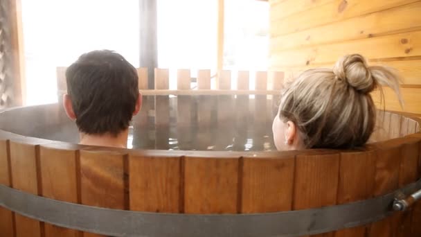 Pareja sentada en agua caliente al aire libre en invierno — Vídeo de stock