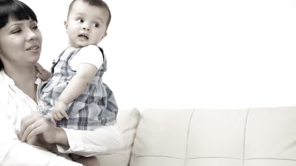 Smilende baby med mor sidder på sofaen – Stock-video