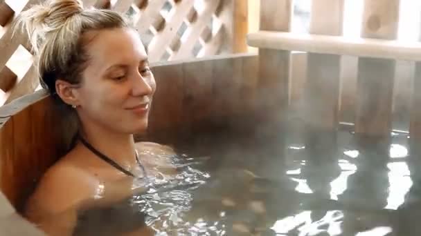 Женщина сидит в горячей воде на открытом воздухе зимой — стоковое видео