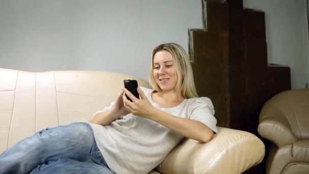 Beautiful girl on sofa speaking by phone — Stock Video