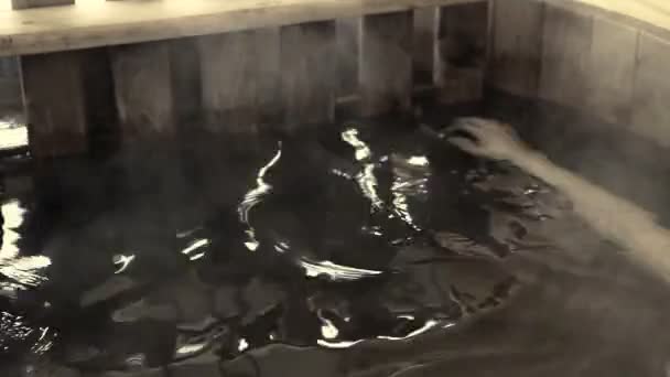 Femme assise dans l'eau chaude en plein air en hiver 